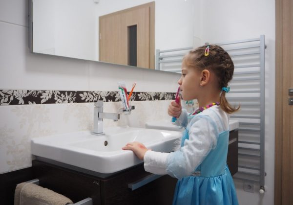 Hnědá koupelna – holčička si čistí zuby před zrcadlem u umyvadla