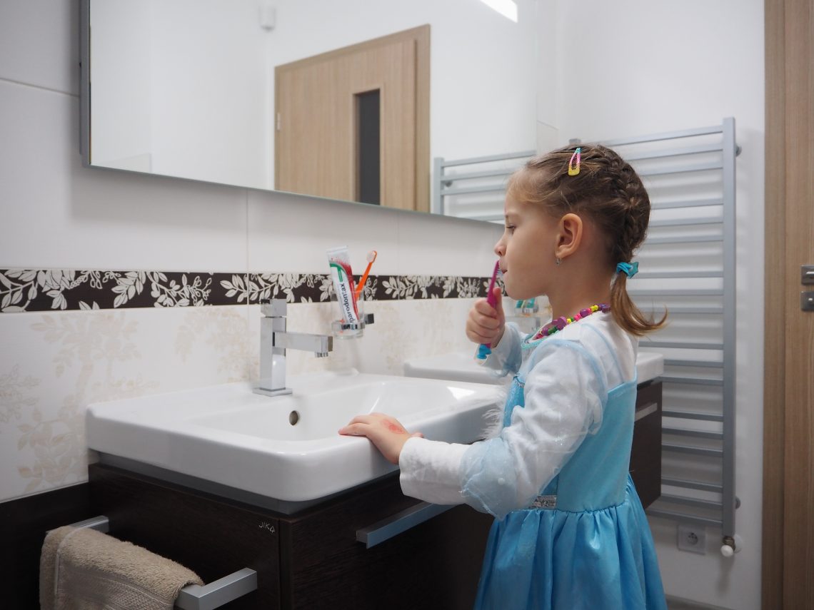 Hnědá koupelna – holčička si čistí zuby před zrcadlem u umyvadla