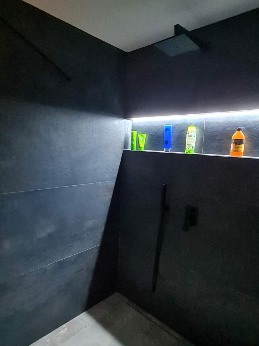 Moderní koupelna v rodinném domě s elegantními černými prvky a LED pásky