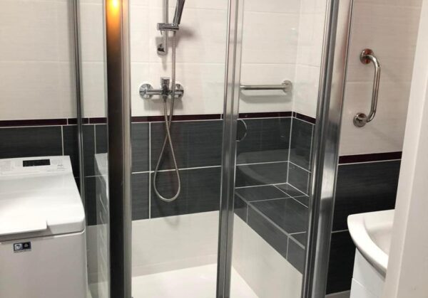 Šedý sprchový kout s vyzděným sedátkem v malé koupelně (Chomutov)