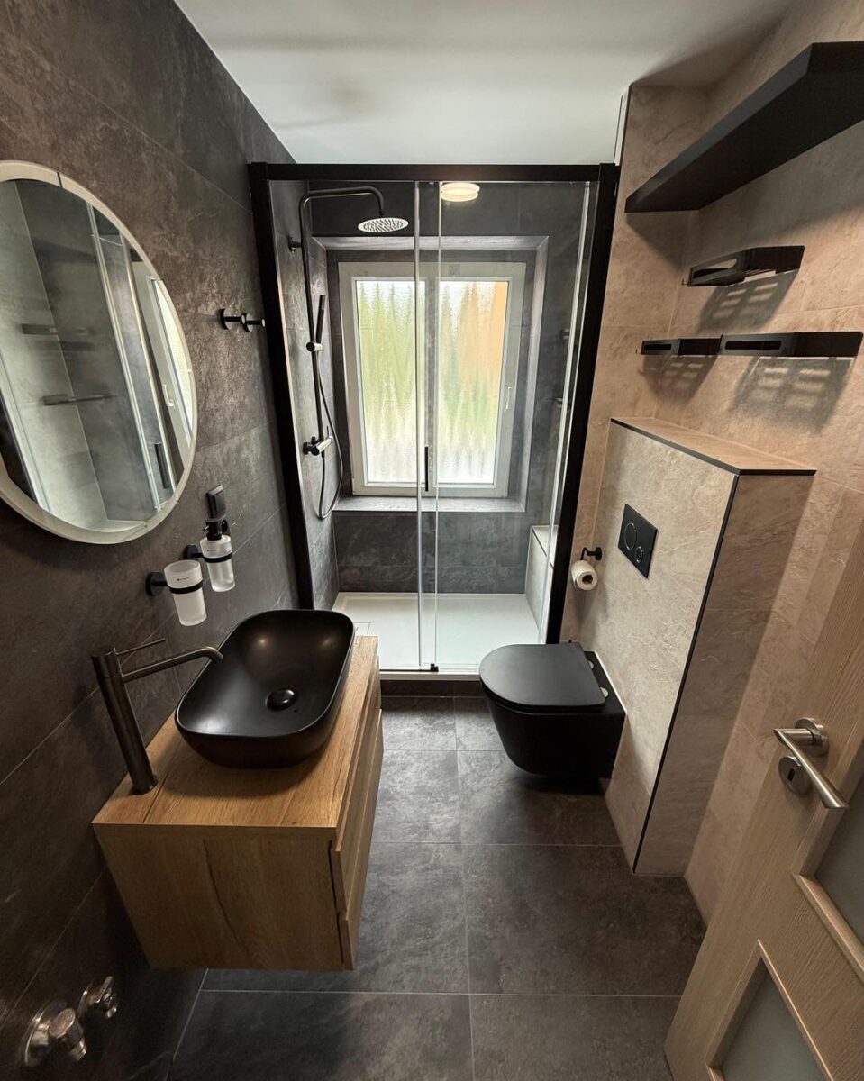 Krásná koupelna s velkoformátovými obklady v dekoru břidlice a černými zařizovacími předměty (Most)