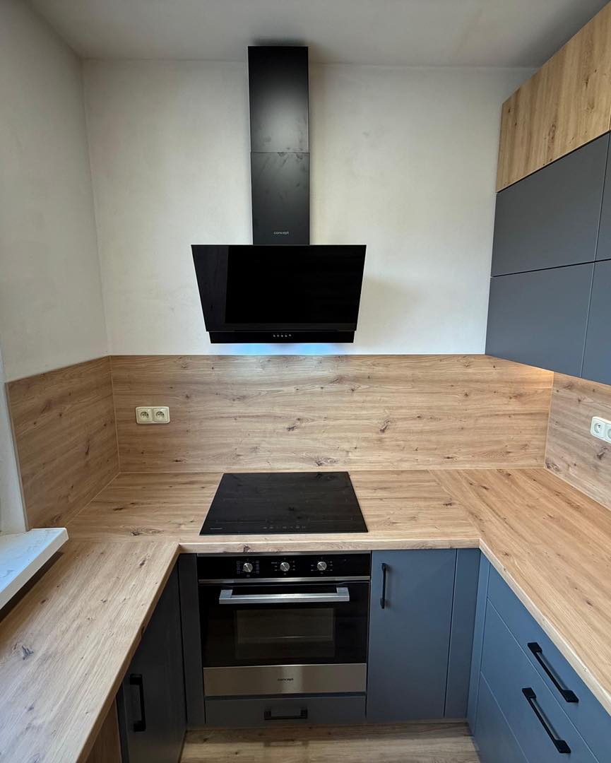 Tmavá kuchyně v kombinaci s dřevodekorem do U (Kadaň)