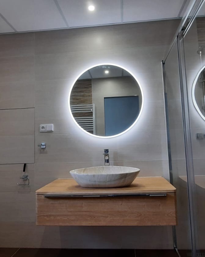 Koupelna plná teplých barev s výraznými prvky jako je podsvícené zrcadlo a mramorové umyvadlo (Most)