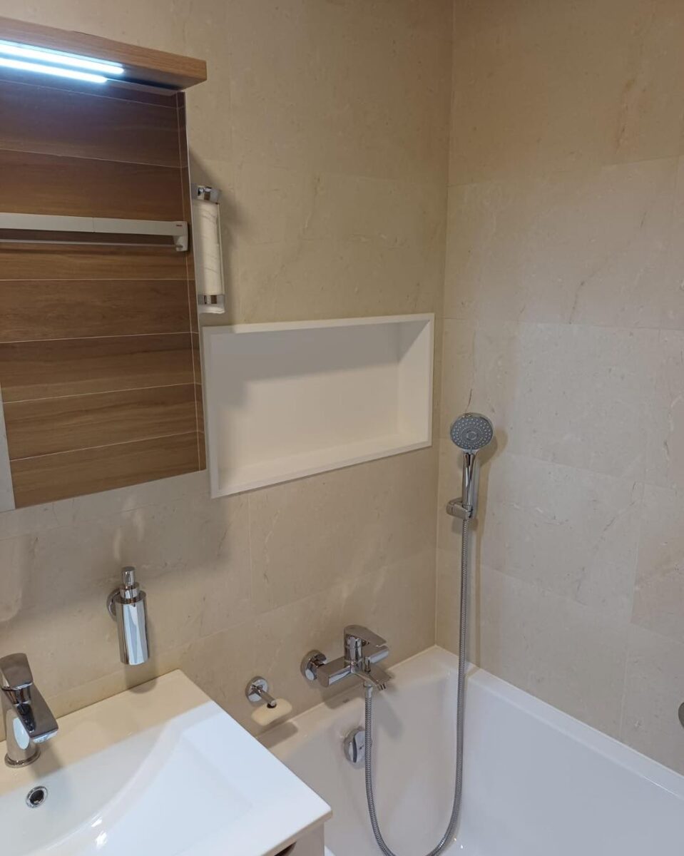 Koupelna v béžových barvách spolu s dekorem dřeva s praktickou nikou (Most)