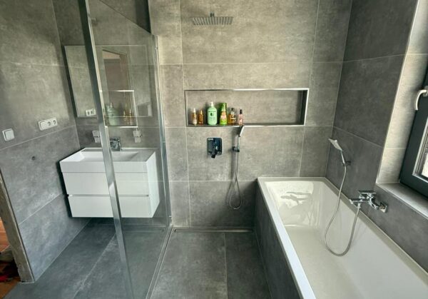 Atypická tmavá koupelna s walk-in sprchou hned vedle vany (Chomutov)