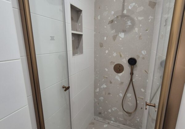 Koupelna s měděnými prvky a béžovošedými obklady s trendy nikami a bidetovou sprškou (Most)