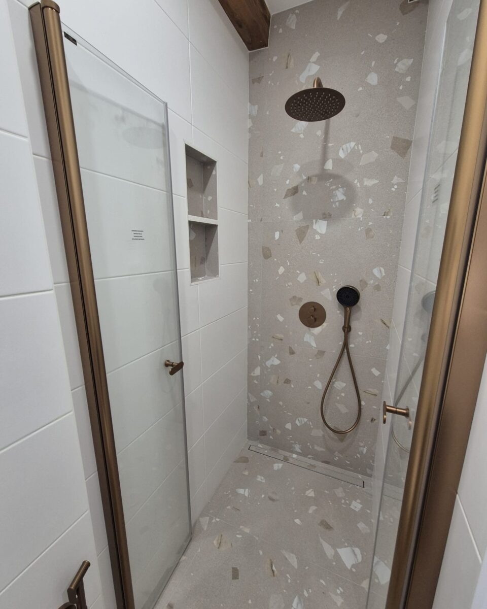 Koupelna s měděnými prvky a béžovošedými obklady s trendy nikami a bidetovou sprškou (Most)