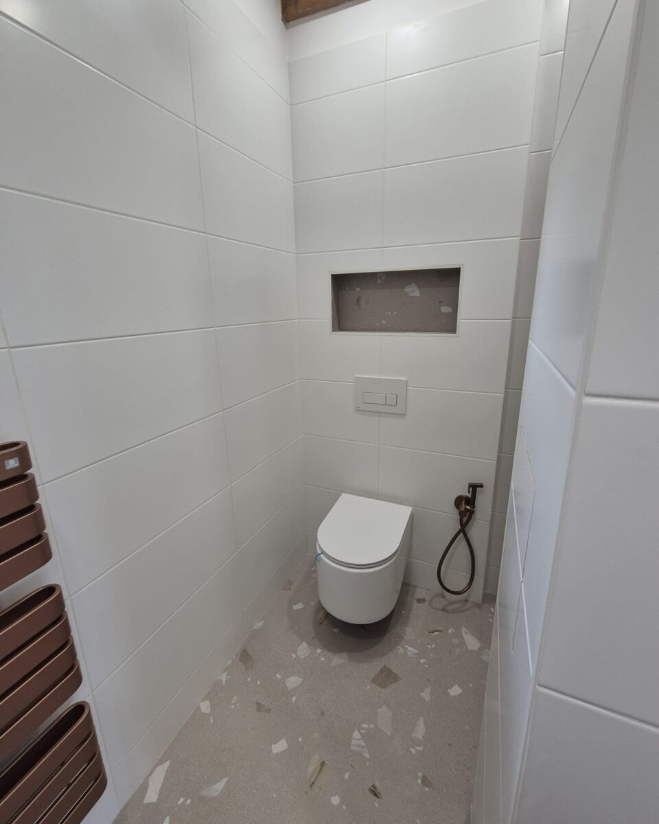 Koupelna s měděnými prvky a béžovošedými obklady s trendy nikami a bidetovou sprškou (Most)